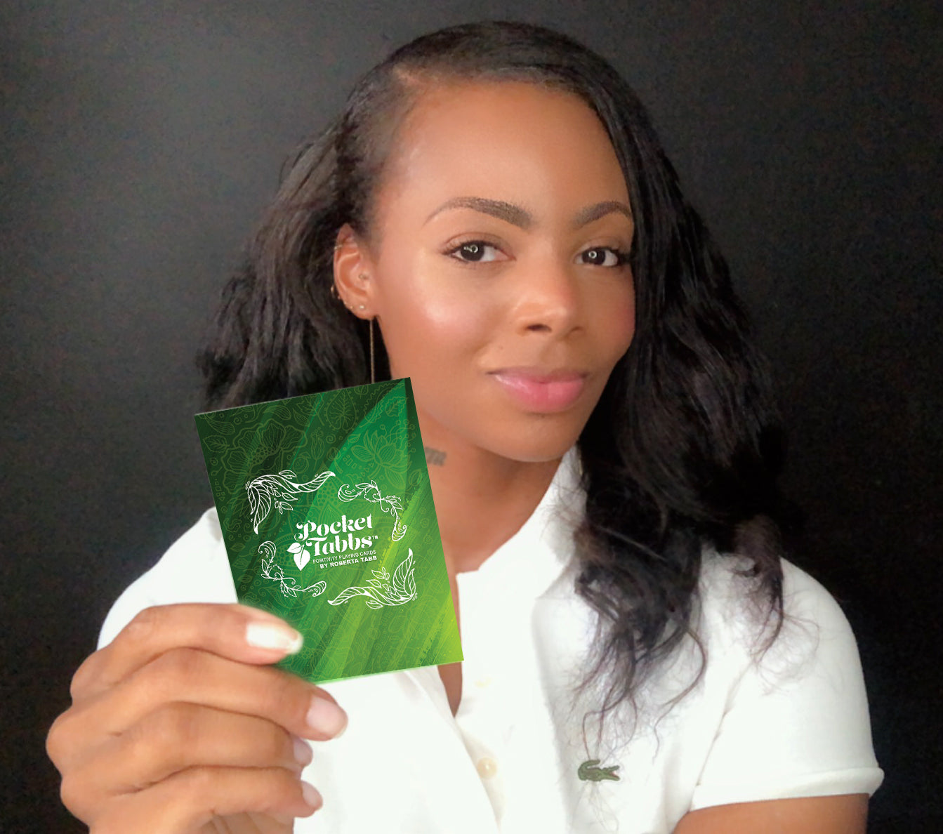 Roberta Tabb holding playing Card with a brand logo against a dark background