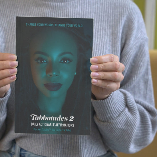 Woman holding Tabbatudes 2 Daily Actionable Affirmations book by Roberta Tabb